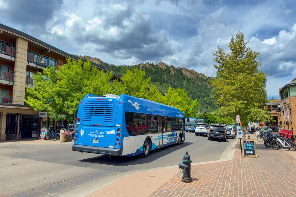 Blue public transit bus on street with mountains in background in Aspen, Colorado.